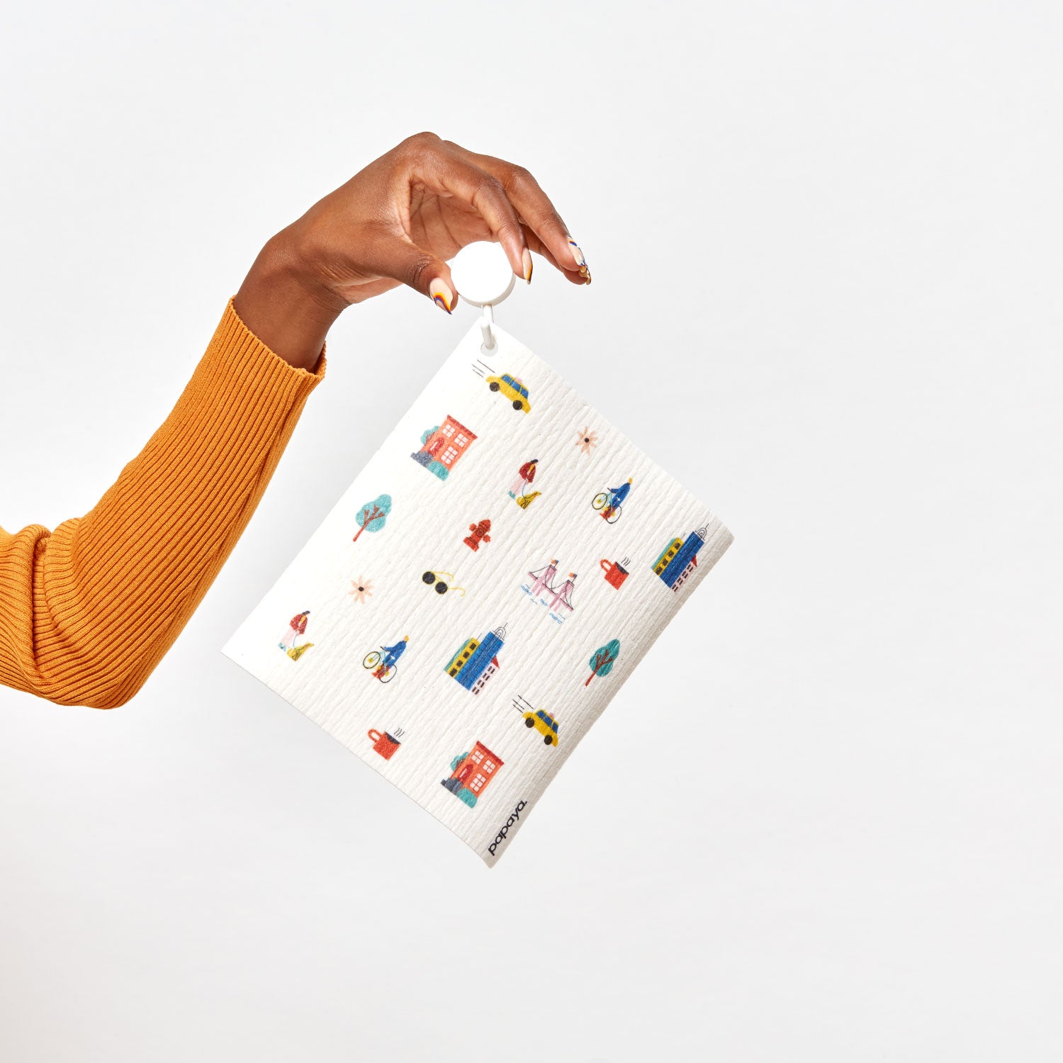 Model holding a hook with a reusable paper towel hanging on it with a city pattern design